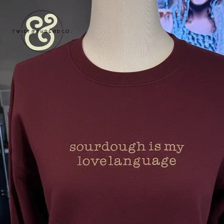 Maroon sweatshirt on mannequin with beige text reading 'sourdough is my lovelanguage' and Twist & Thread Co. logo