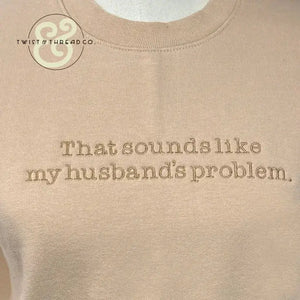 Beige sweatshirt with embroidered text that reads 'That sounds like my husband's problem' and Twist & Thread Co. logo