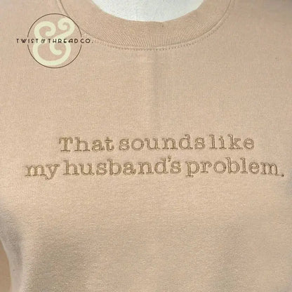Beige sweatshirt with embroidered text that reads 'That sounds like my husband's problem' and Twist & Thread Co. logo