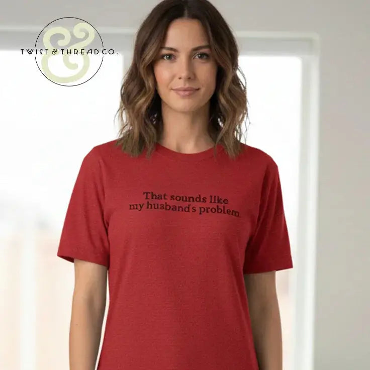 Woman wearing red t-shirt with black text that reads 'That sounds like my husband's problem' in bright room