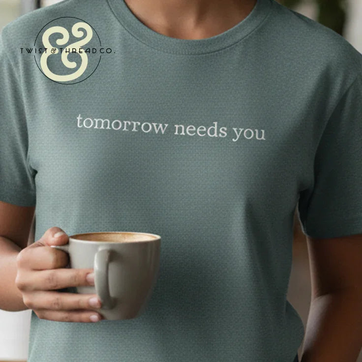 Custom embroidered Twist & Thread Co. t-shirt with 'tomorrow needs you' text, person holding mug