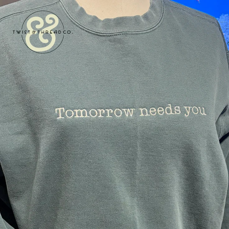 Custom embroidered sweatshirt with 'Tomorrow needs you' text by Twist & Thread Co.