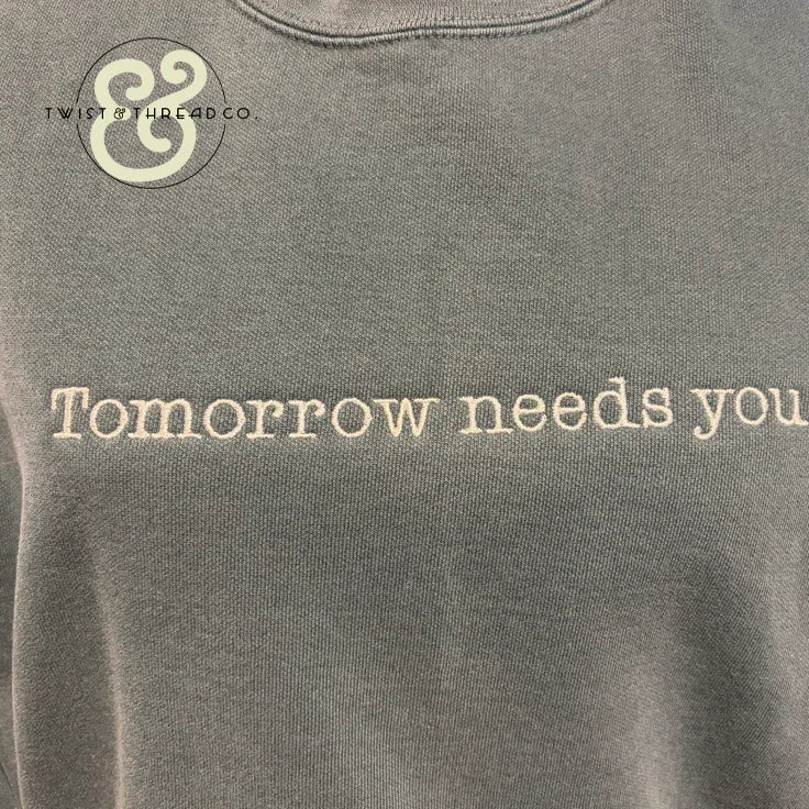 Custom embroidered hoodie with 'Tomorrow needs you' text by Twist & Thread Co.