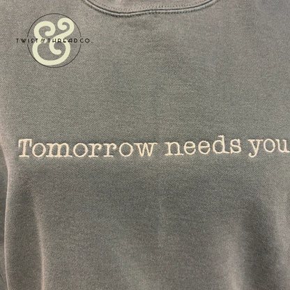 Custom embroidered hoodie with 'Tomorrow needs you' text by Twist & Thread Co.