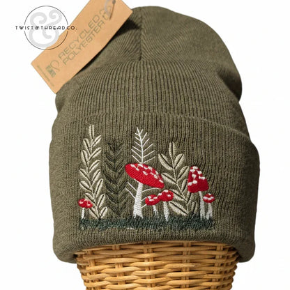 Olive green knit winter hat with embroidered red mushrooms and leaves, recycled polyester tag